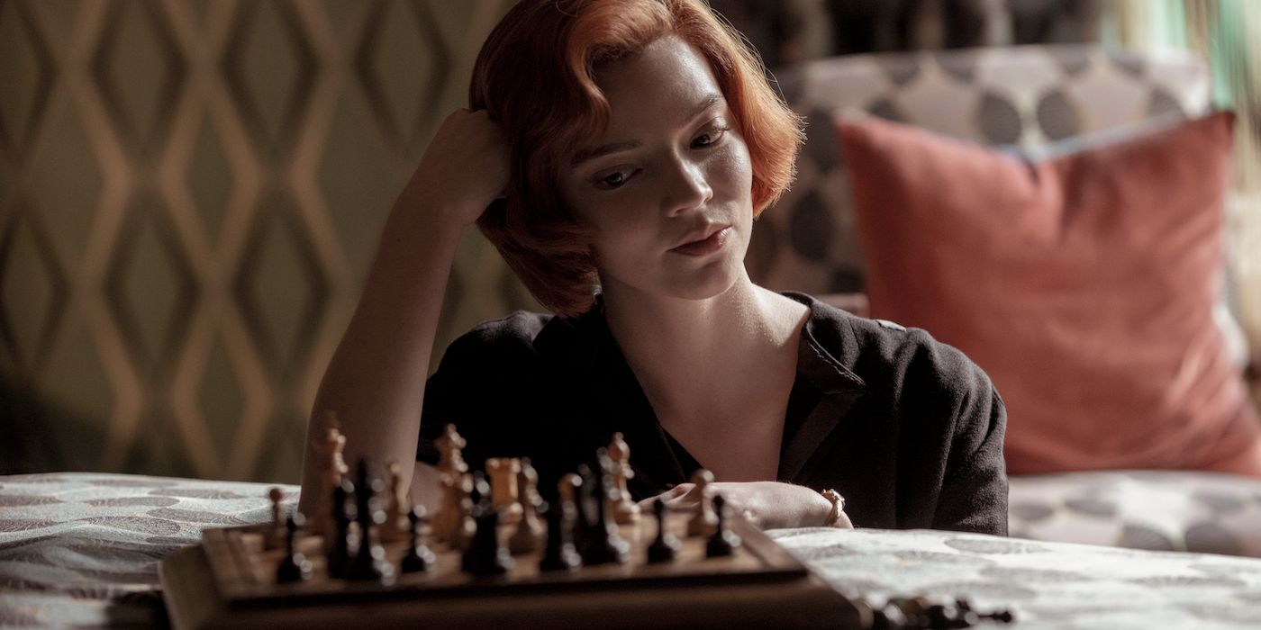 Anya Taylor-Joy as Beth Harmon sits on a bed and plays chess in The King's Gambit.