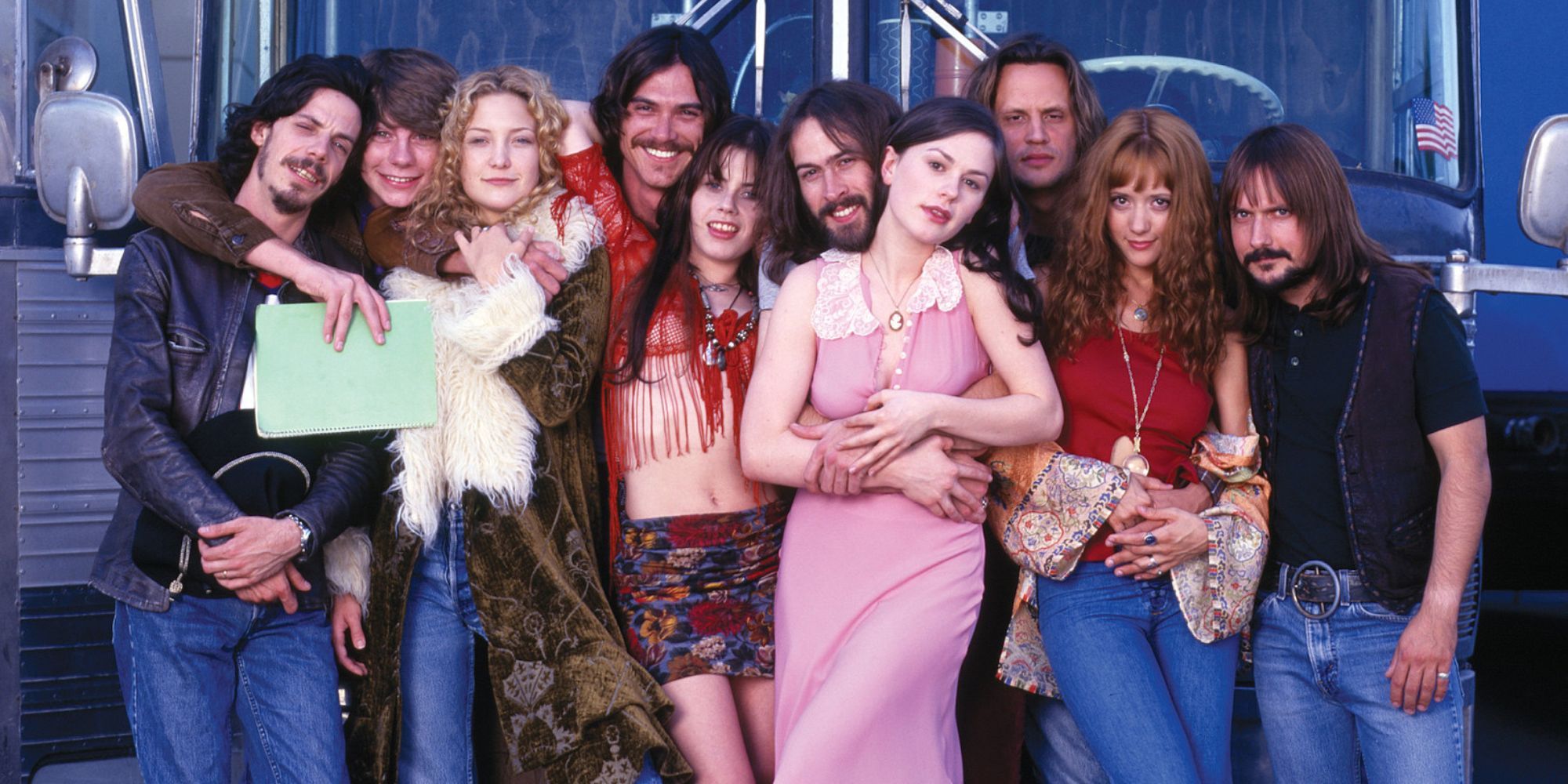 The cast of Almost Famous pose in front of a bus.