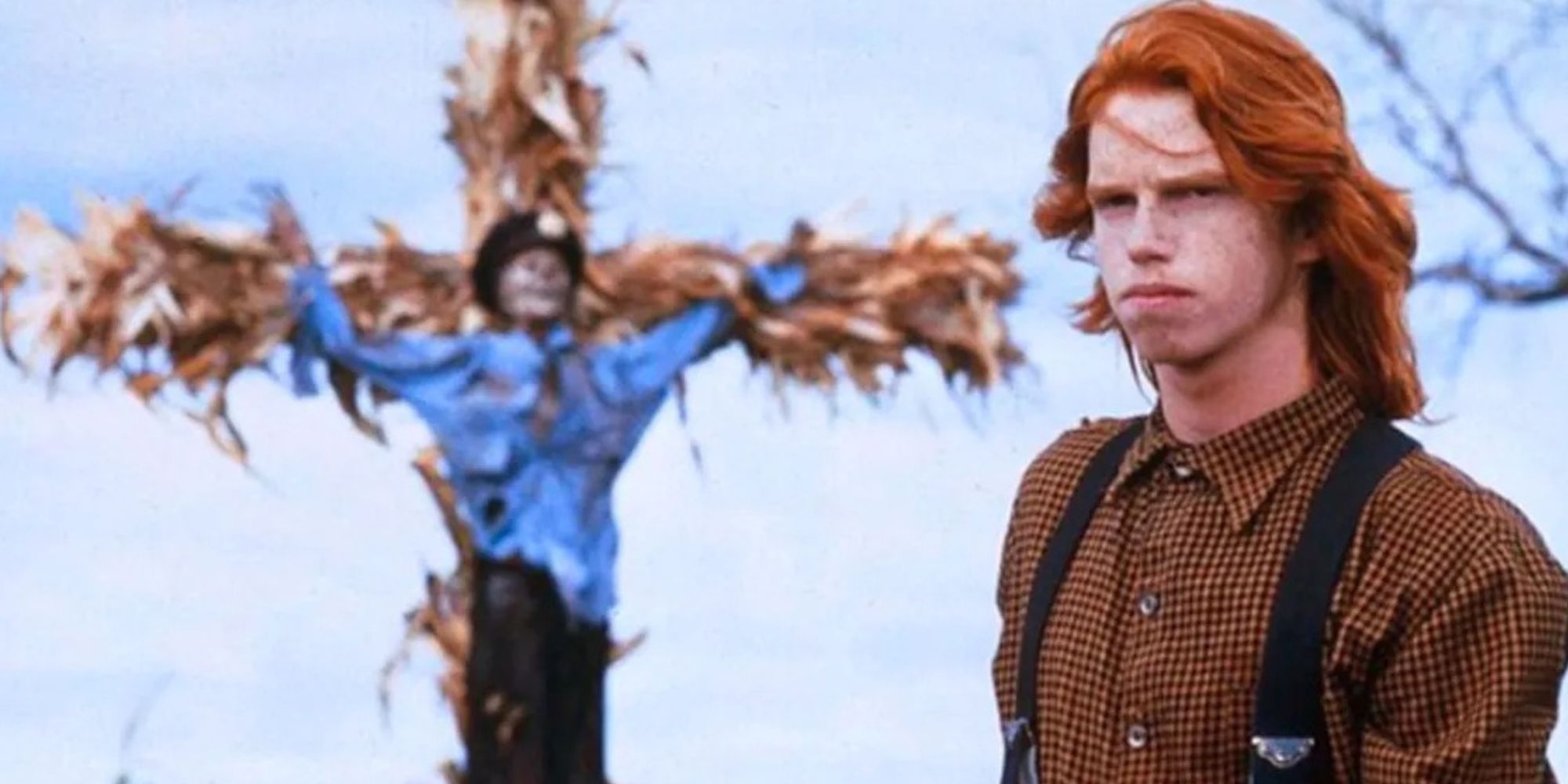 A teenager stands next to a crucified effigy