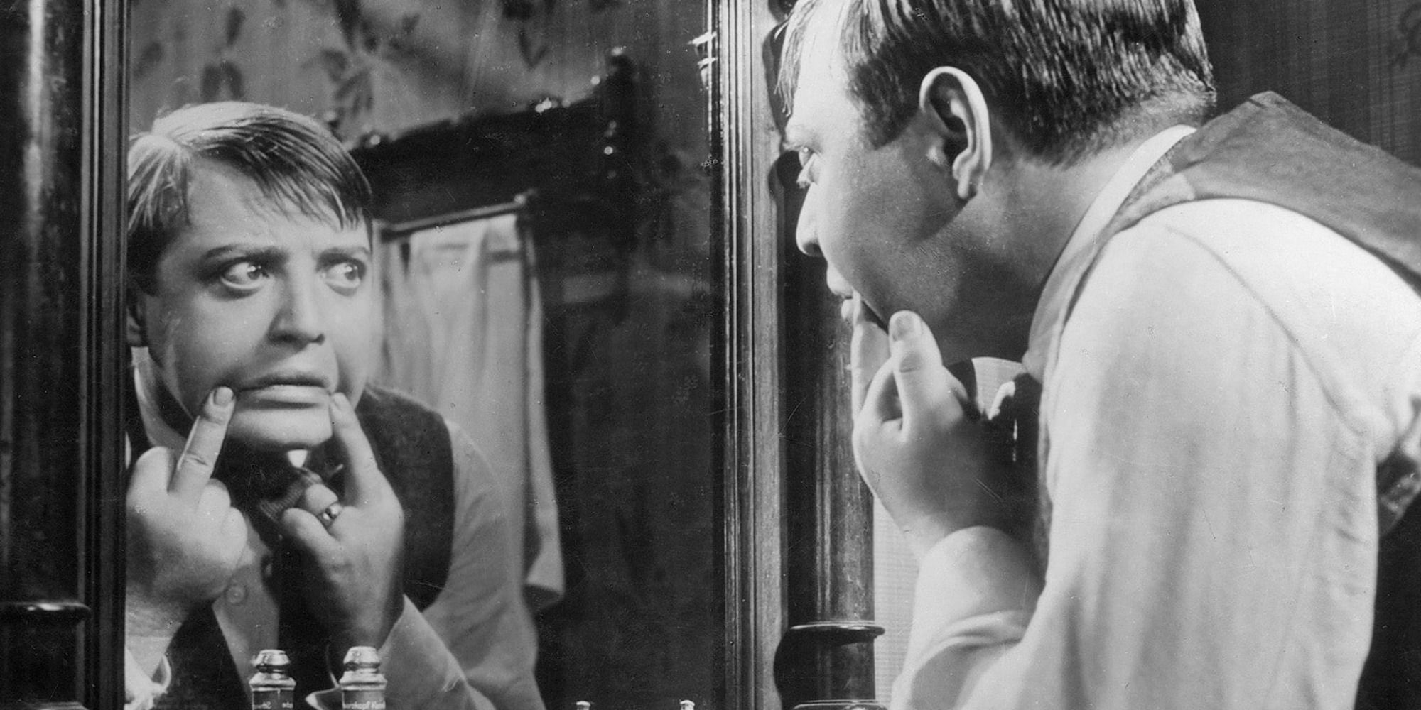 man touching his face while looking in the mirror