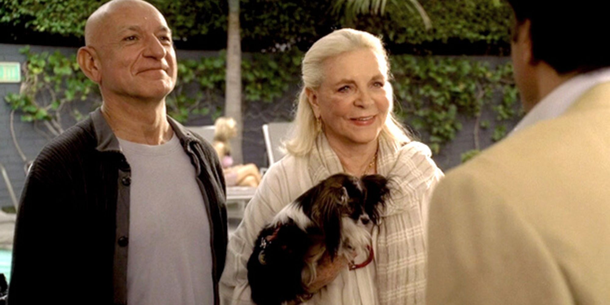 Ben Kingsley stands next to Lauren Bacall, who is holding a dog, both looking at someone who has his back to the camera in The Sopranos.