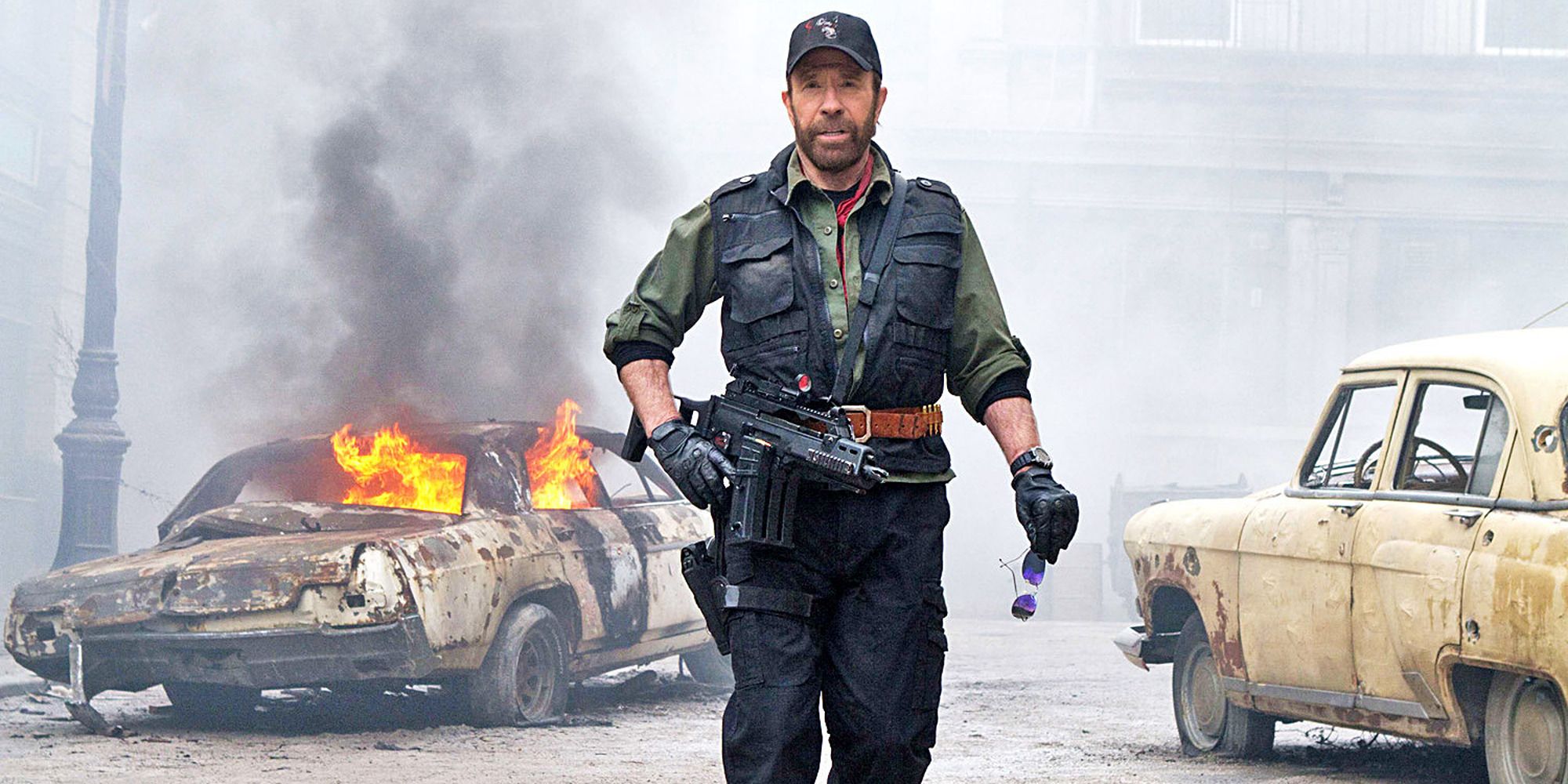 a man in military uniform walks away from a burning car