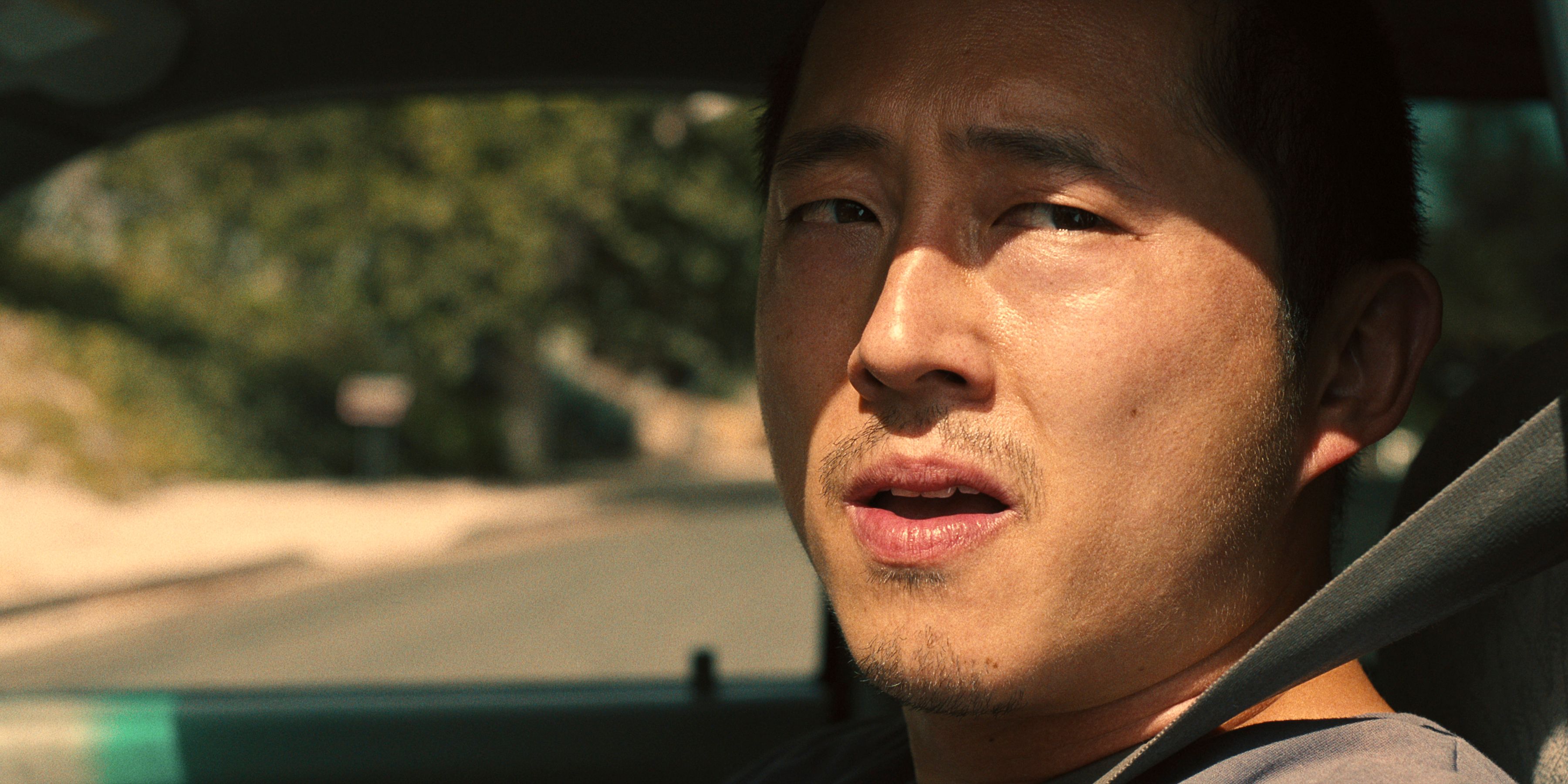 Steven Yeun as Danny Cho looks out the side window of the driver from the car in BEEF.