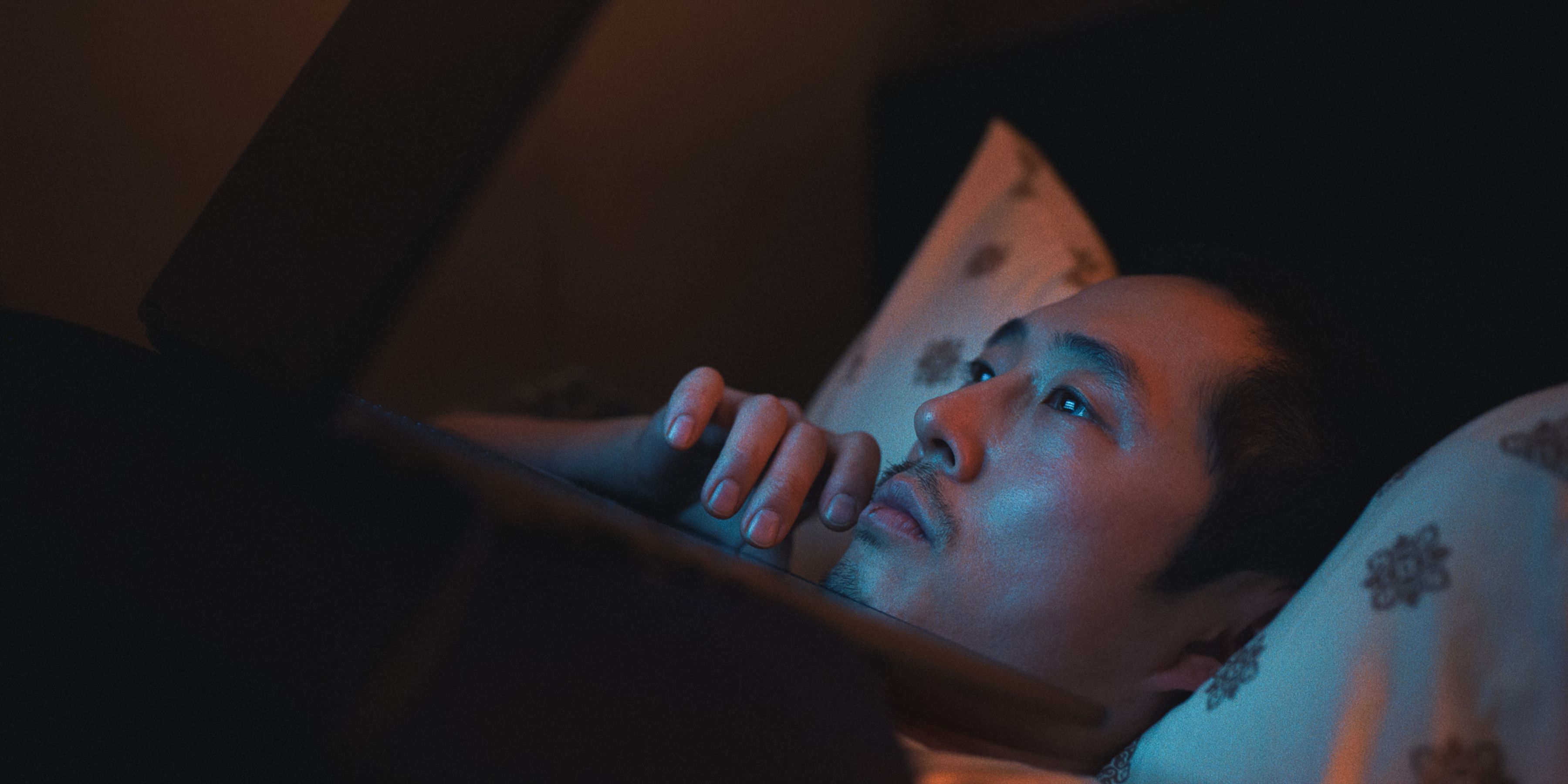 Steven Yeun as Danny Cho in bed with his phone at BEEF