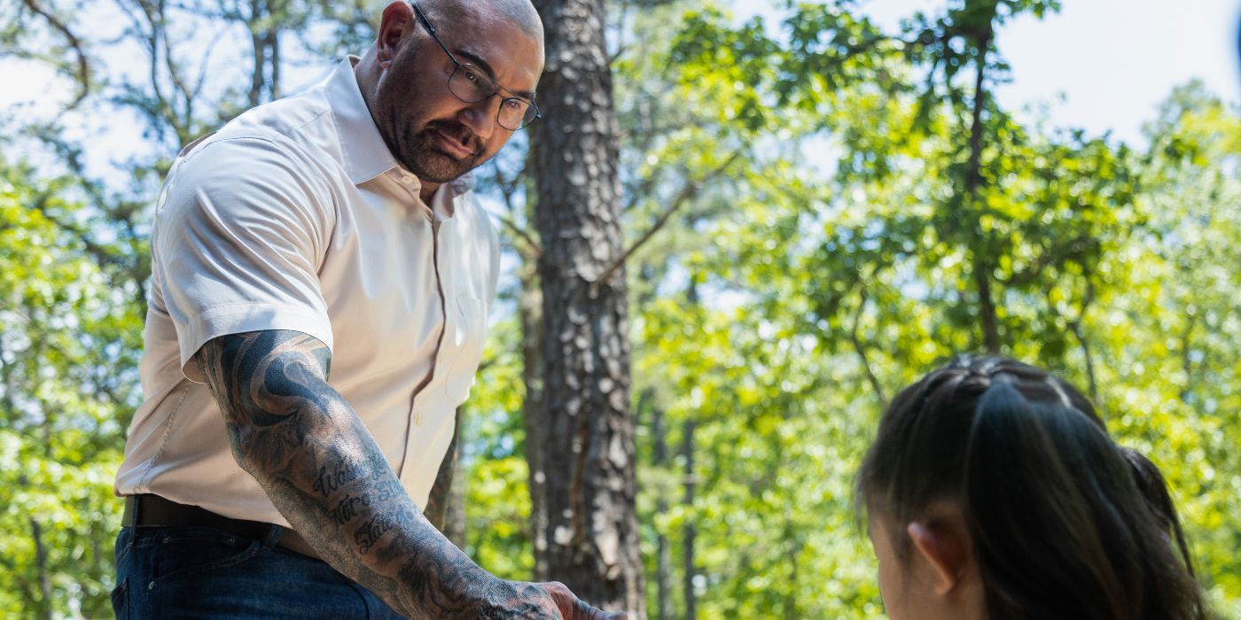 Leonard approaches a young girl in the woods in the 2023 film Knock at the Cabin.