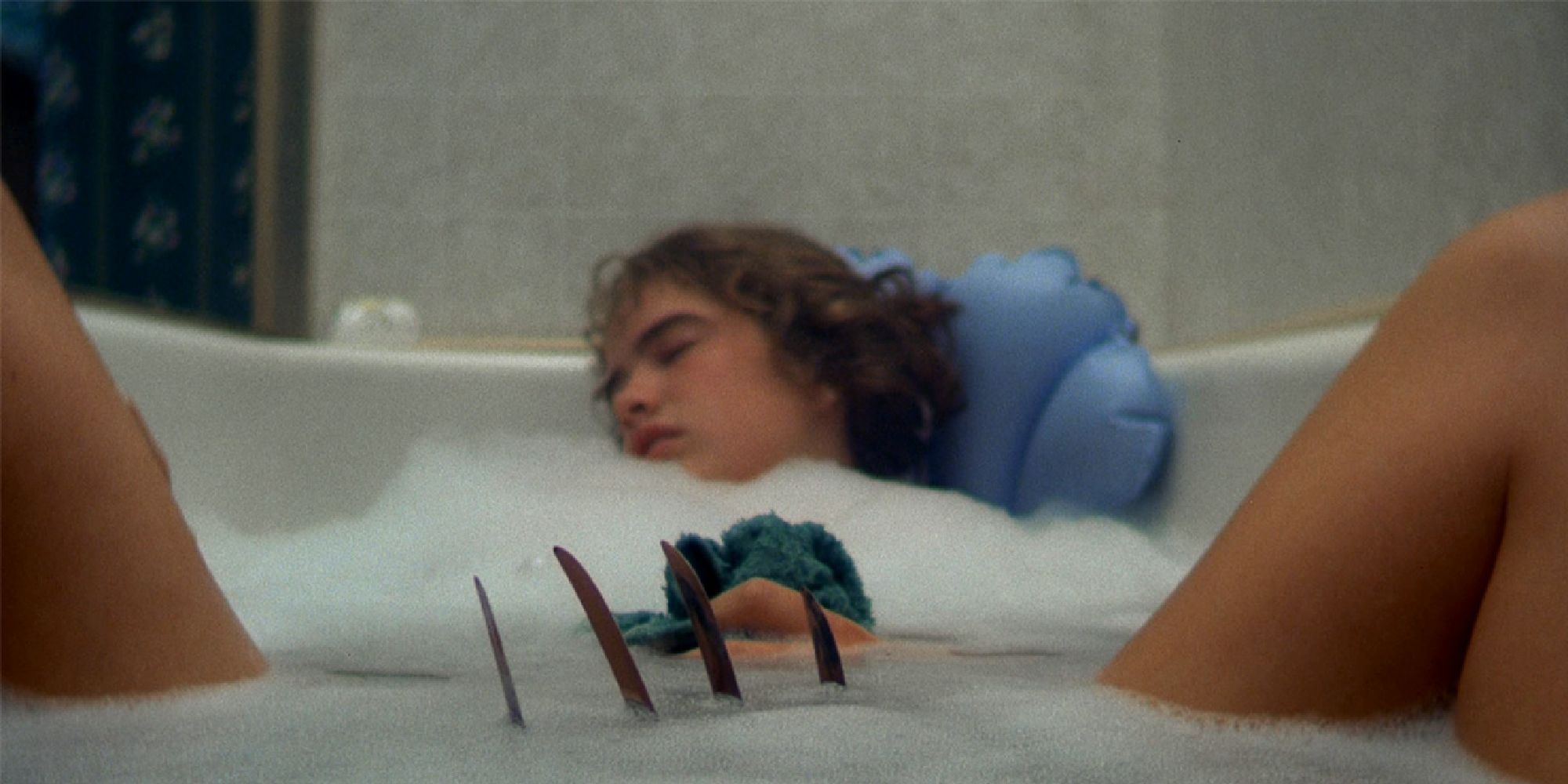 Freddy Krueger's claws are about to attack Heather Langenkamp's character in the bathtub in A Nightmare on Elm Street.