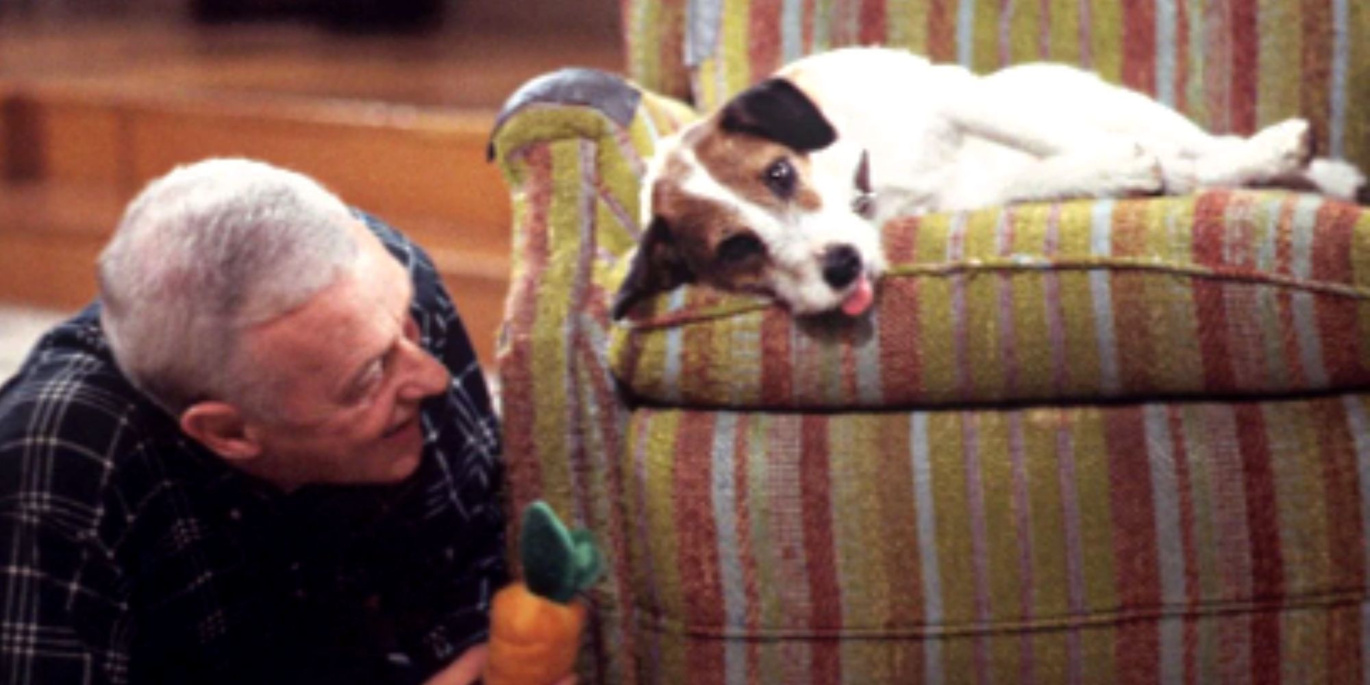 John Mahoney lies on his stomach and holds a toy in front of Eddie on a chair in Frazier.