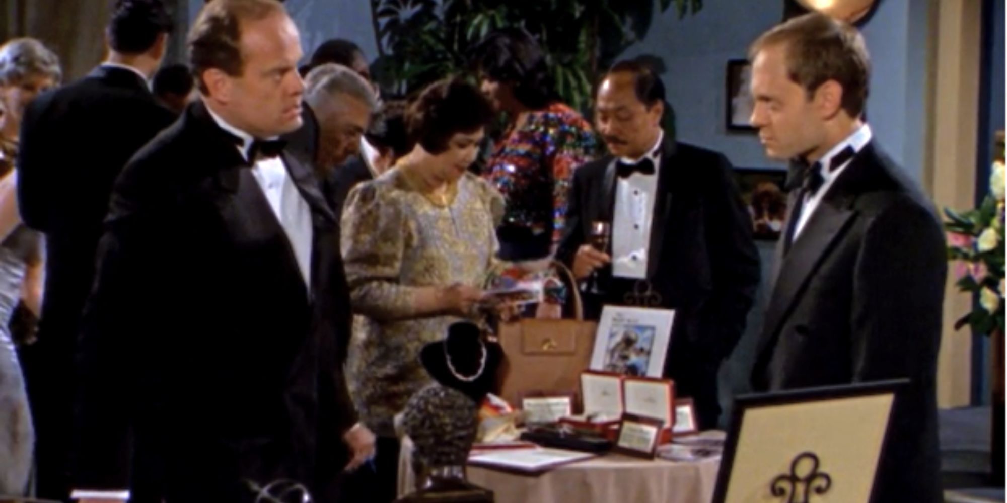 Kelsey Grammer stands opposite David Hyde Pierce next to a table in Fraser.