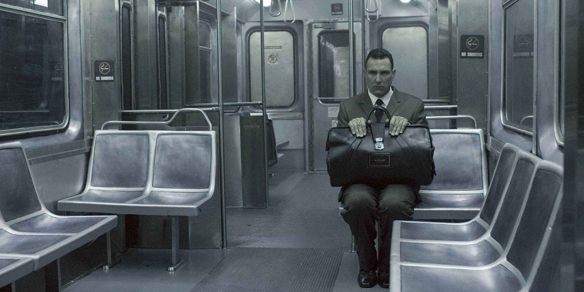 A man sits with a briefcase on a train