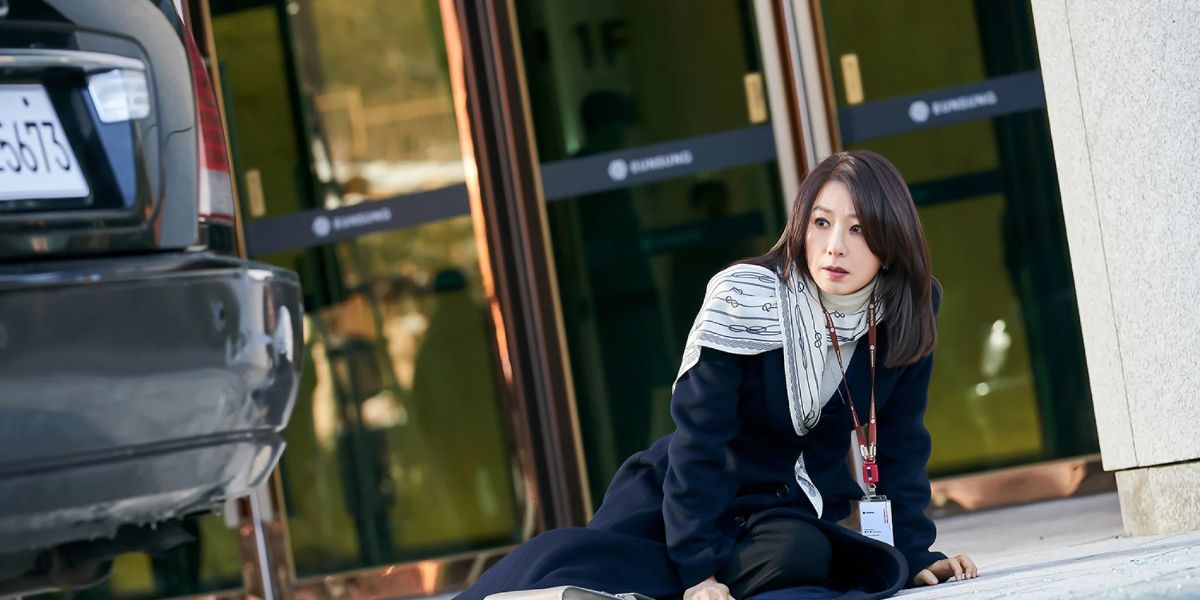 Kim Hee Ae lies on the ground in front of a car in the Netflix K-Drama Queenmaker.