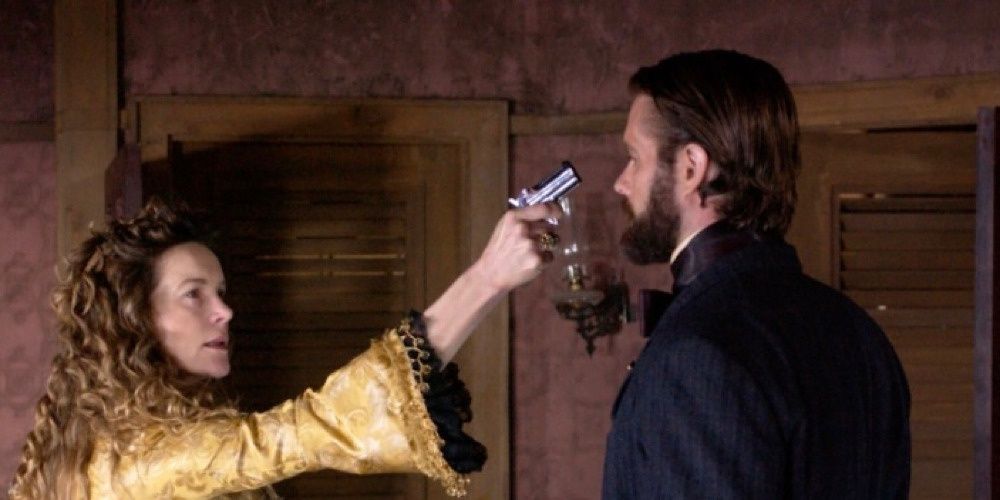 Maddie points a gun at Francis Walcott in Chez Ami. 