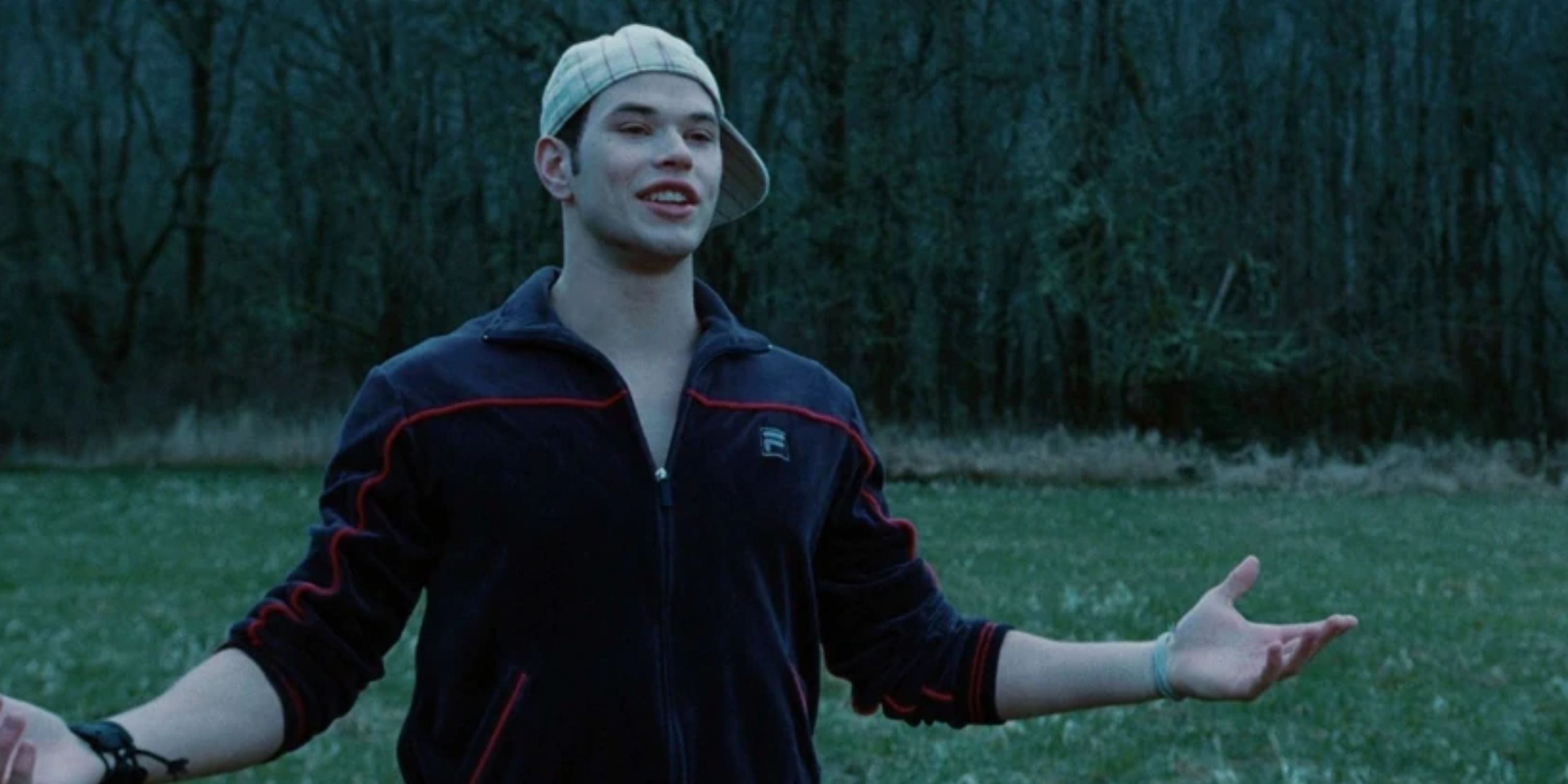 Kellan Lutz as Emmett Cullen in Twilight wearing a baseball cap backwards in a field.