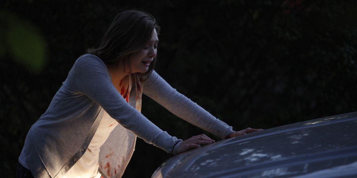 Elizabeth Olsen rests her hands on a car in distress in Quiet House