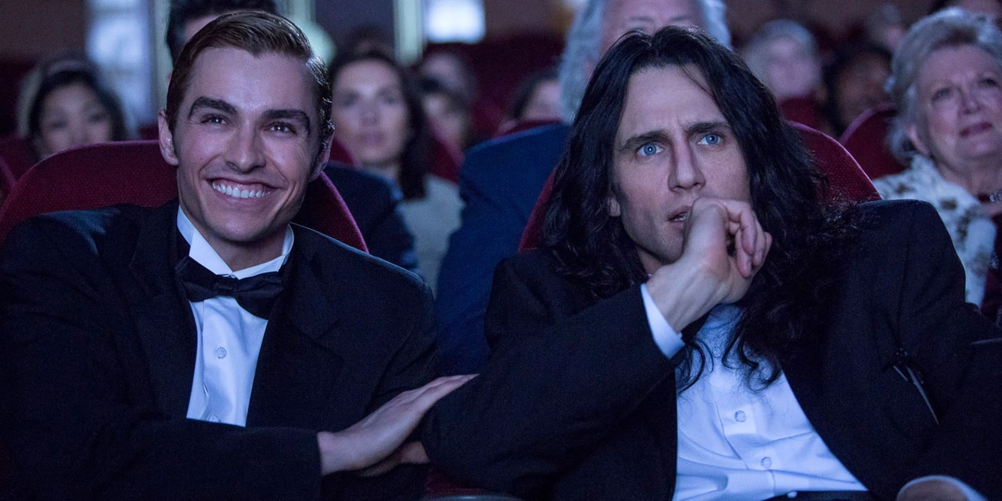 A man looks at the cinema screen with delight, and his companion looks with horror