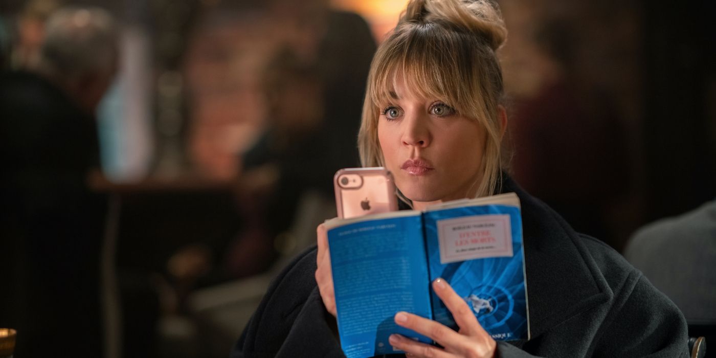 Cassie takes a photo with her phone while holding an open book in Flight Attendant.
