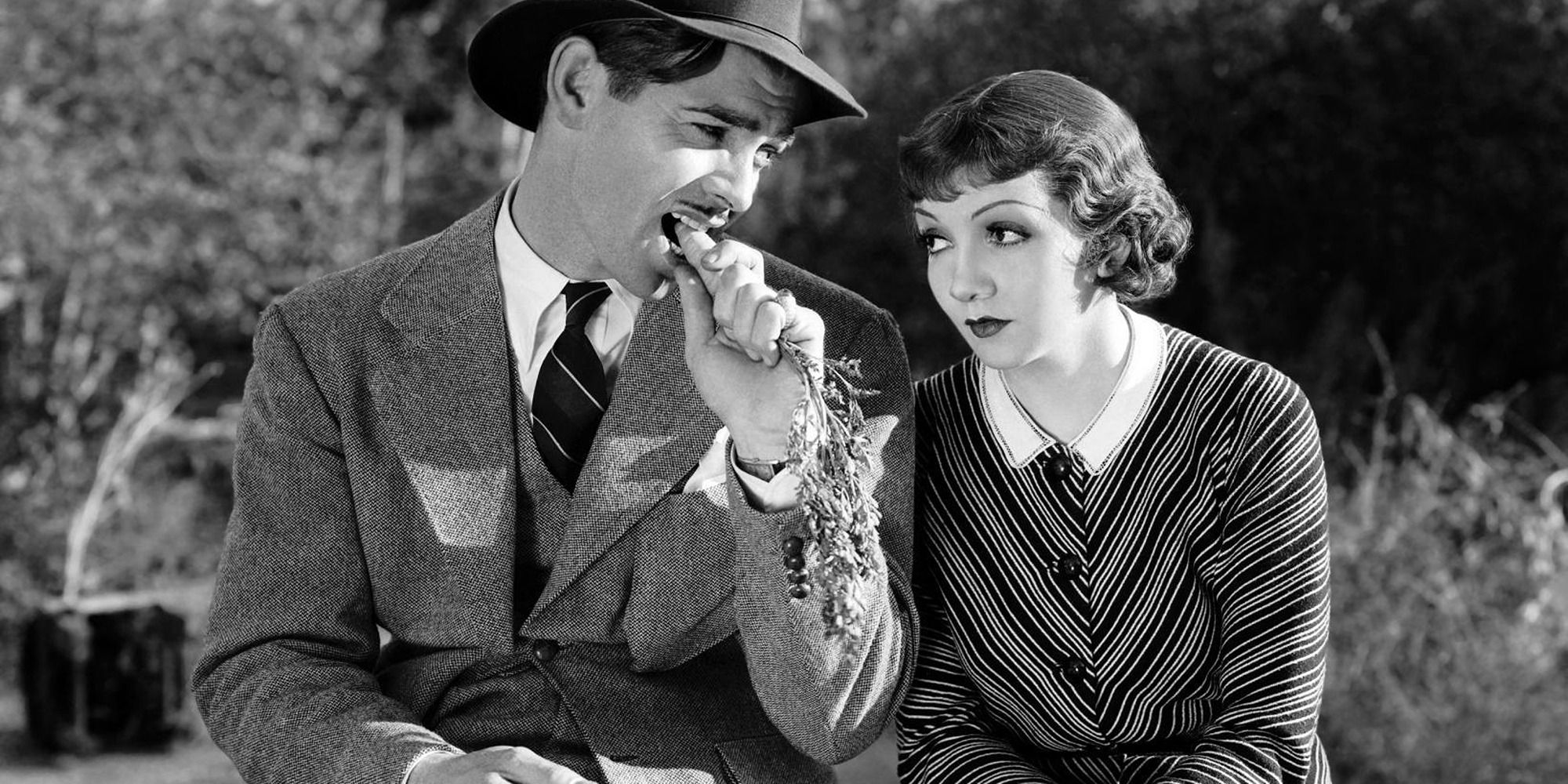Peter and Ellie sit side by side on the side of the road in It Happened One Night.