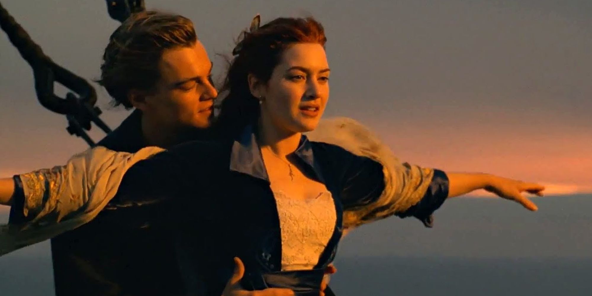 Jack hugs Rose from behind while her arms are outstretched in front of the bow of the boat.
