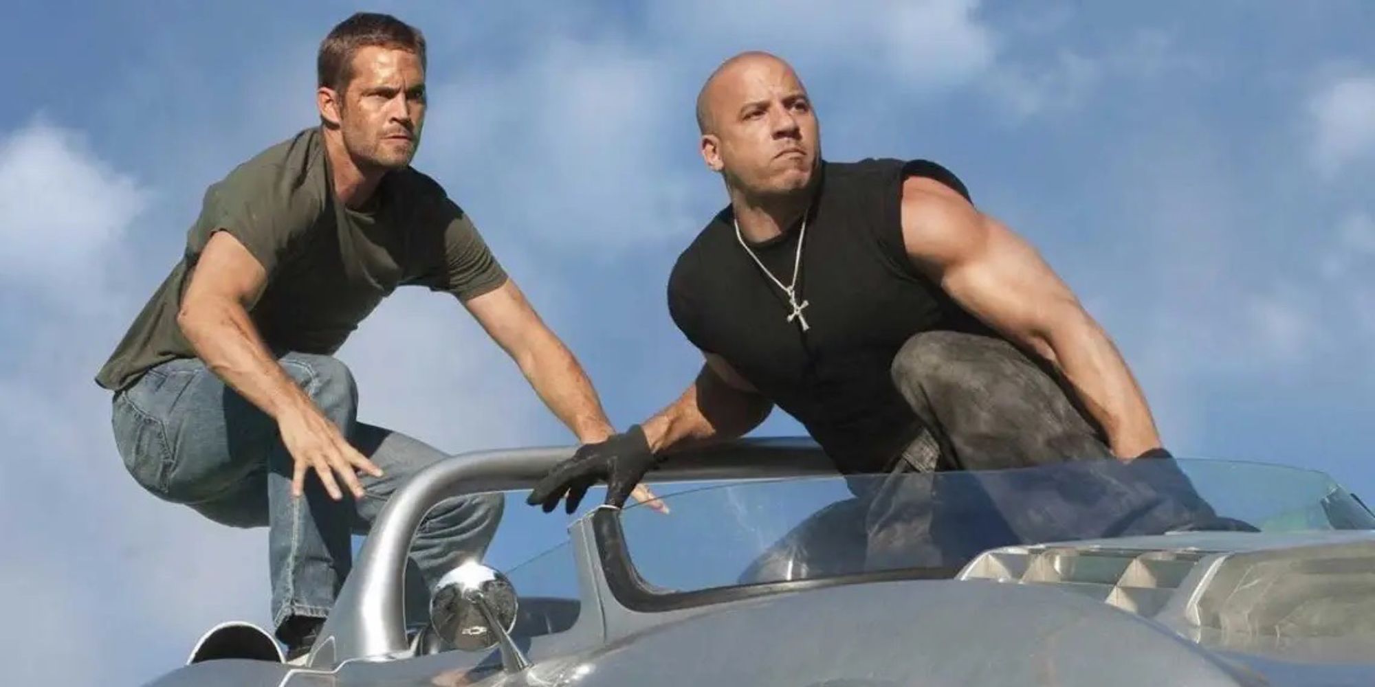 Two men ride on the roof of a car