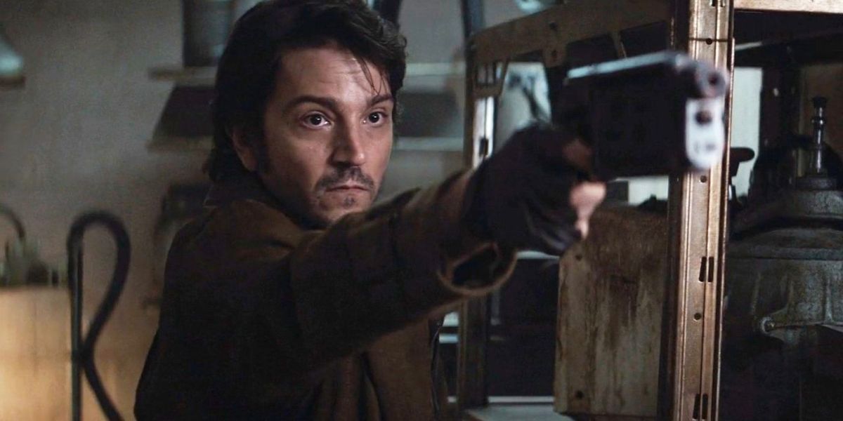 Cassian Andor points a gun at someone off-screen in Andor.