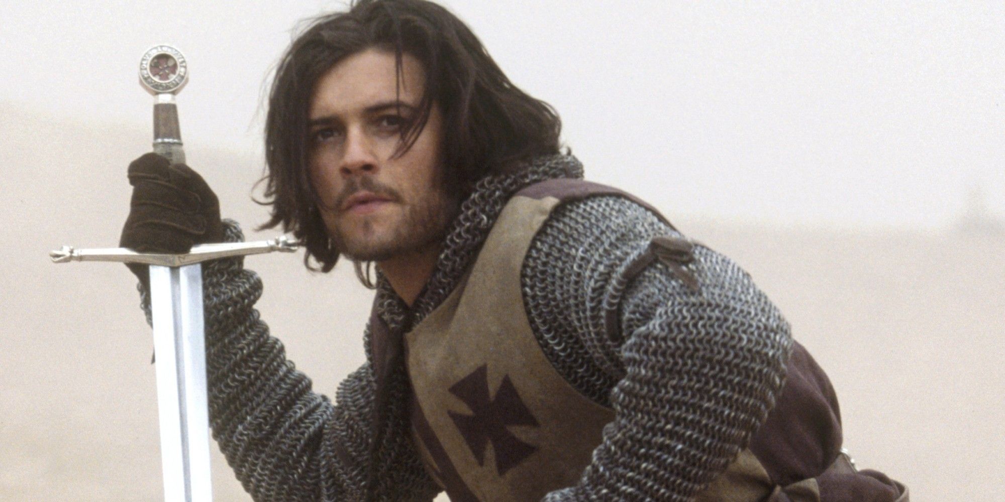 Orlando Bloom as Balian kneeling with a sword in the Kingdom of Heaven
