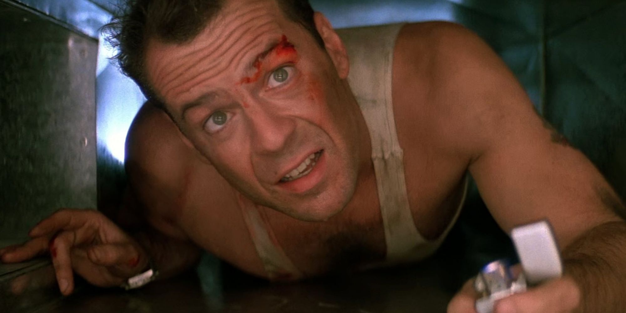 Bruce Willis as John McClain crawling through an air vent with a lighter in his hand in Die Hard.