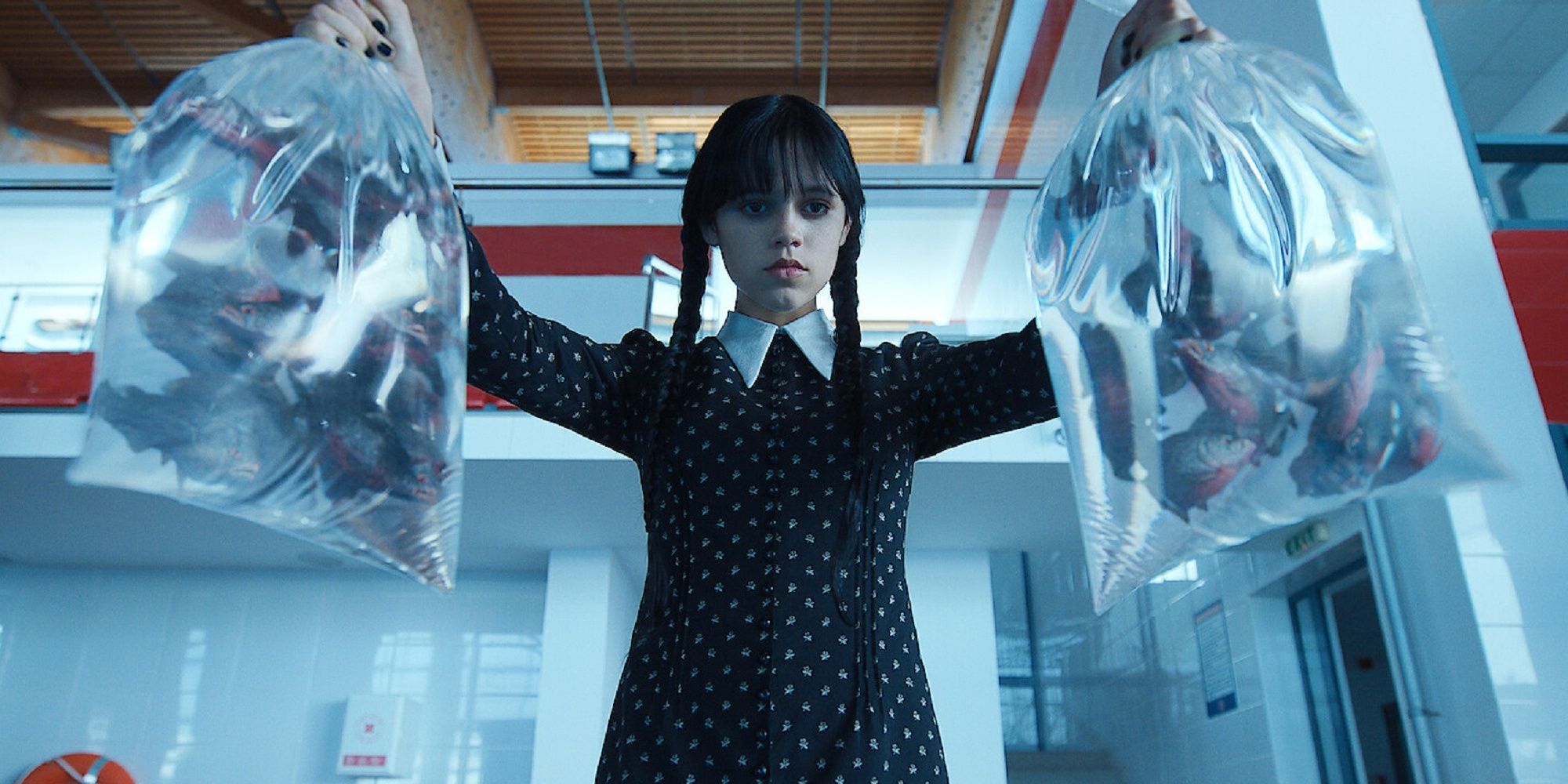 Wednesday Addams holds bags of piranhas at Nevermore Academy's swimming pool.