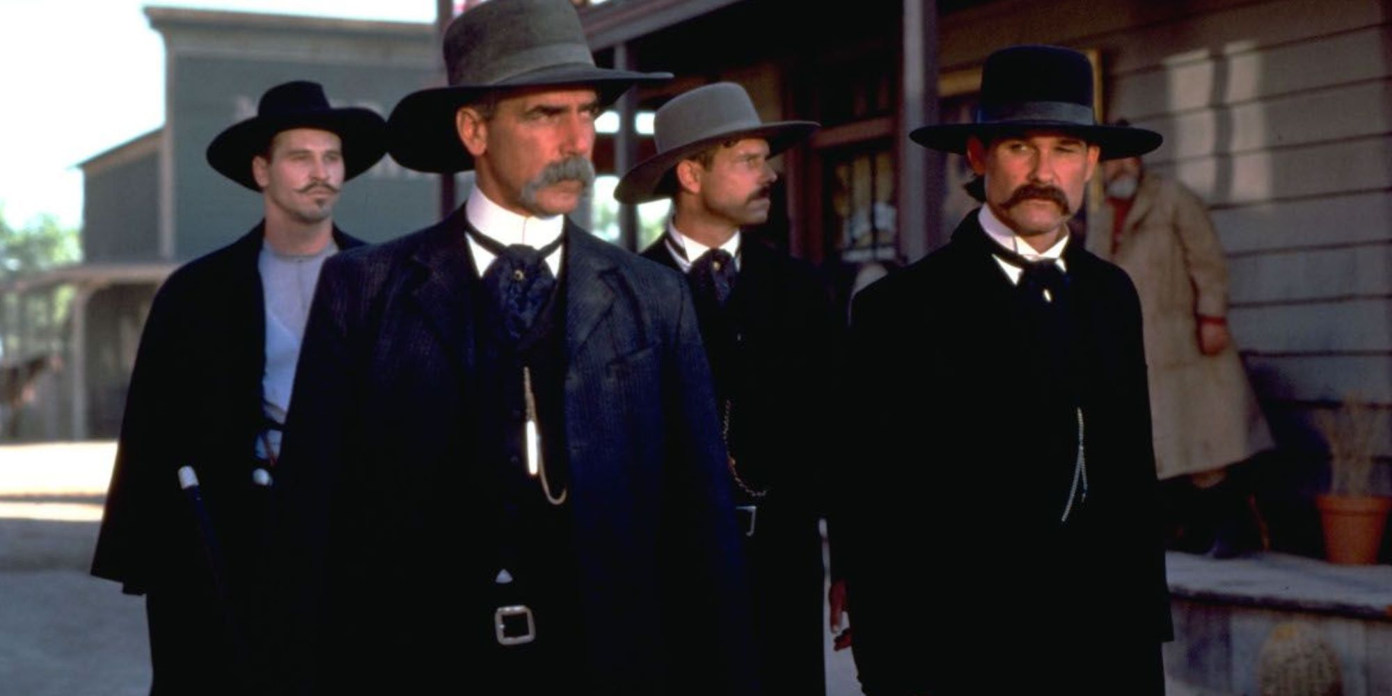 Sam Elliott and Kurt Russell stand next to each other and look back at Tombstone.