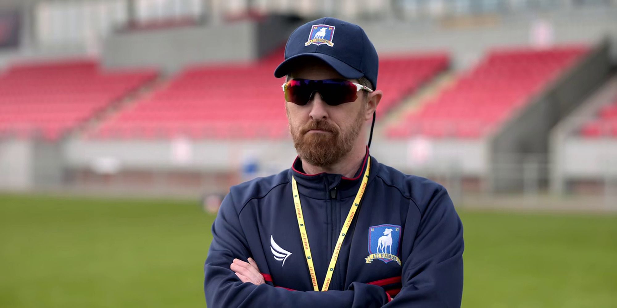 football coach on the field, wearing sunglasses and a cap