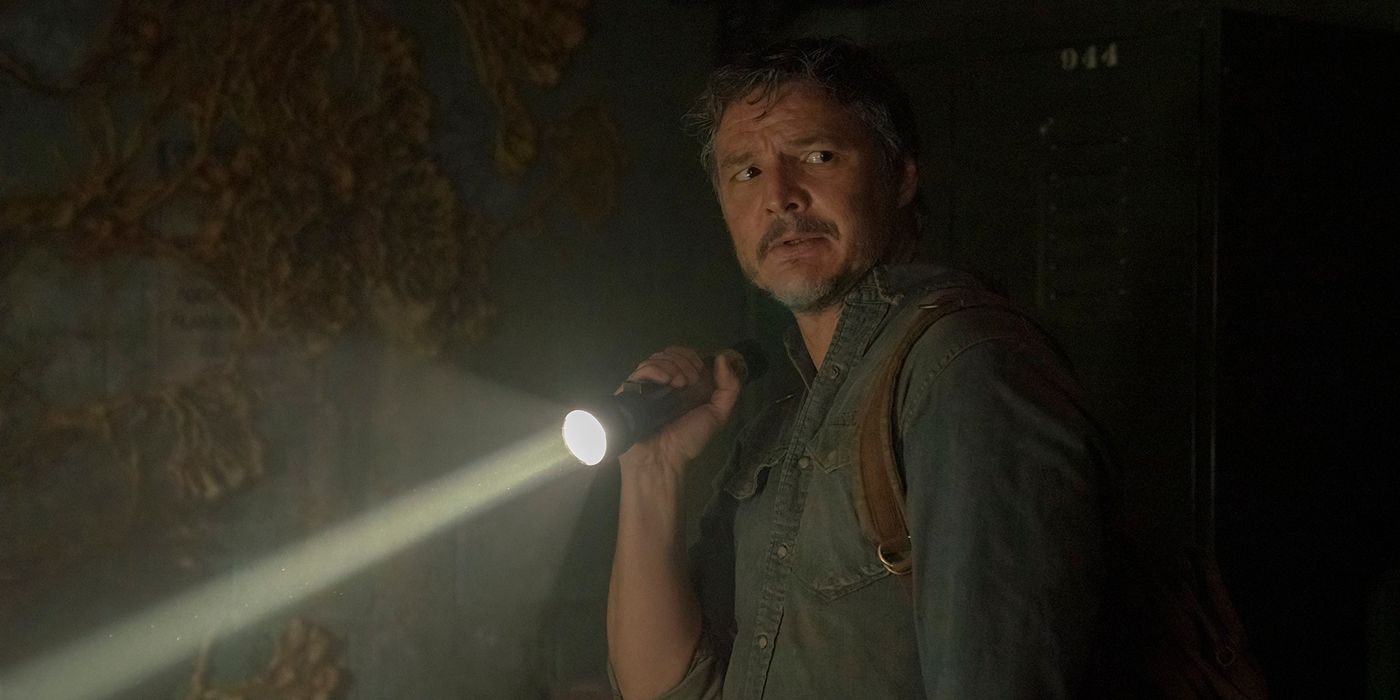 Joel from The Last of Us looks scared and holds a lit flashlight.