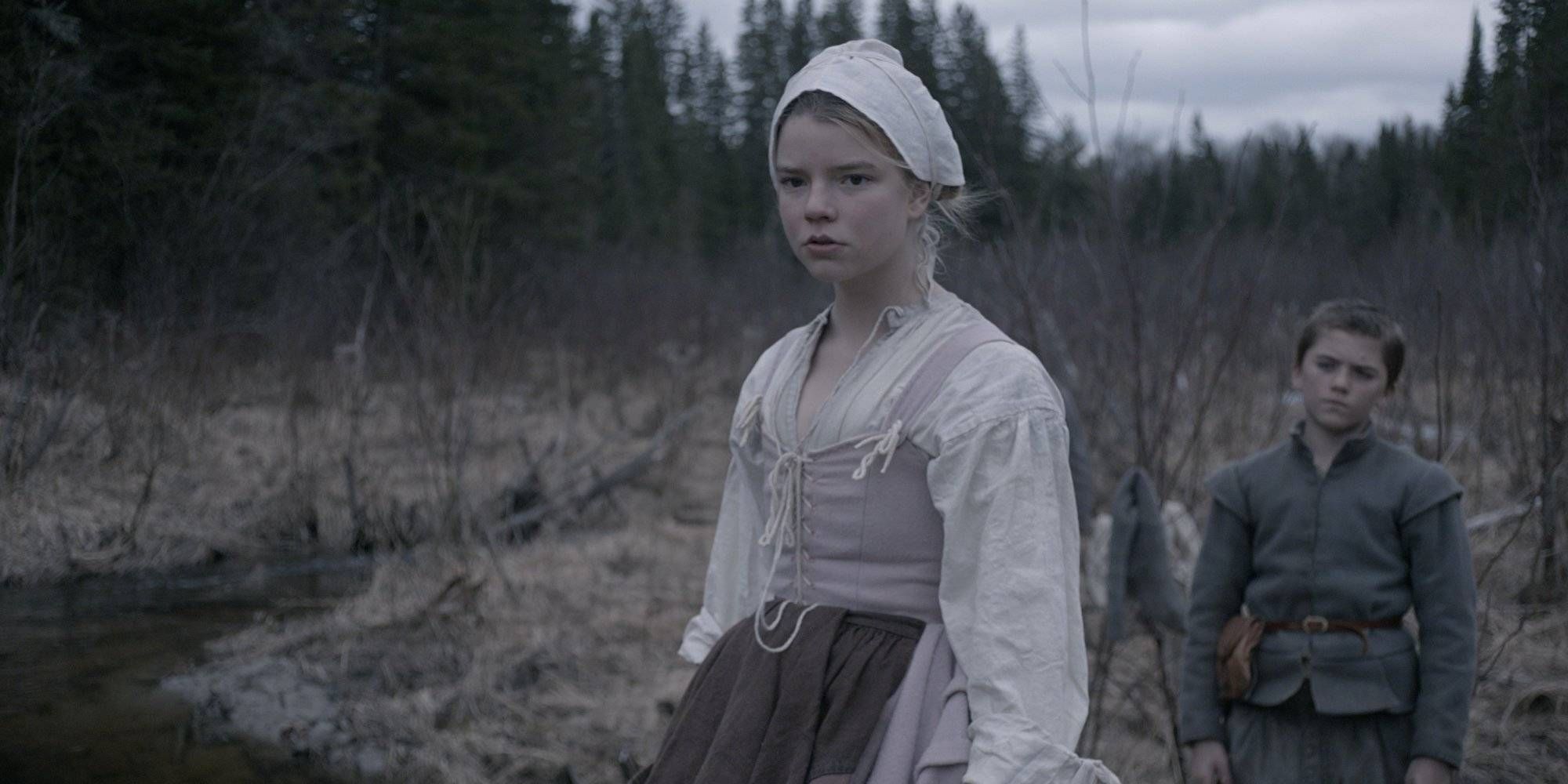 Anya Taylor Joy standing in a spooky field in The Witch