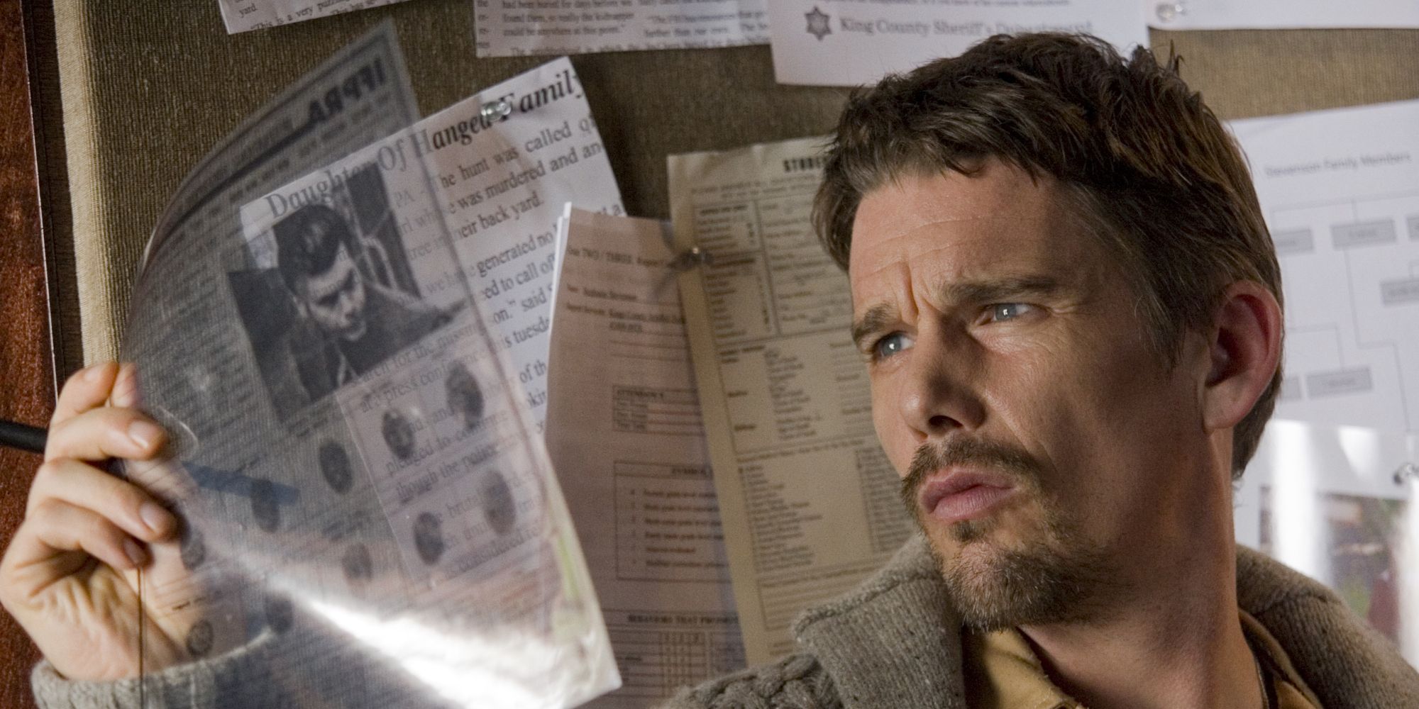 Ethan Hawke looking at a piece of newspaper in Sinister