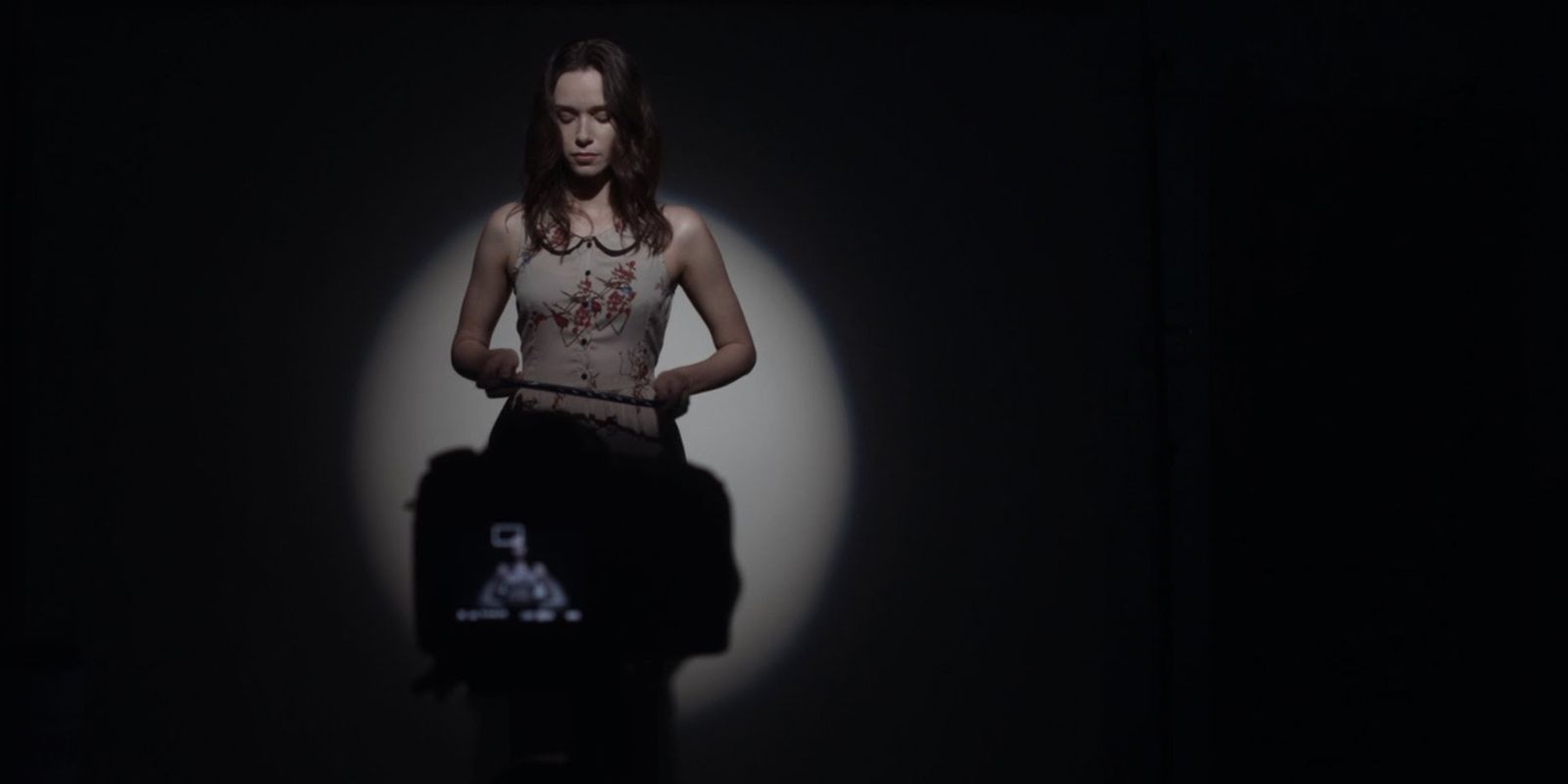 A woman stands in front of a camera in a dimly lit listening room.