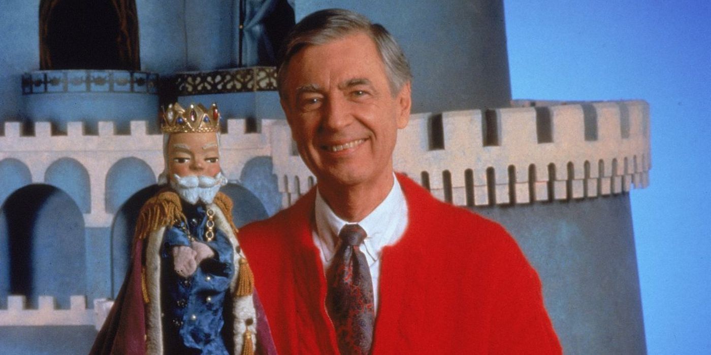Fred Rogers smiles and holds the king's puppet in Mister Rogers' area.
